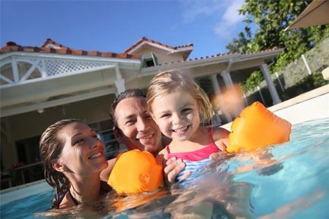 parents in pool with small child wearing water wings