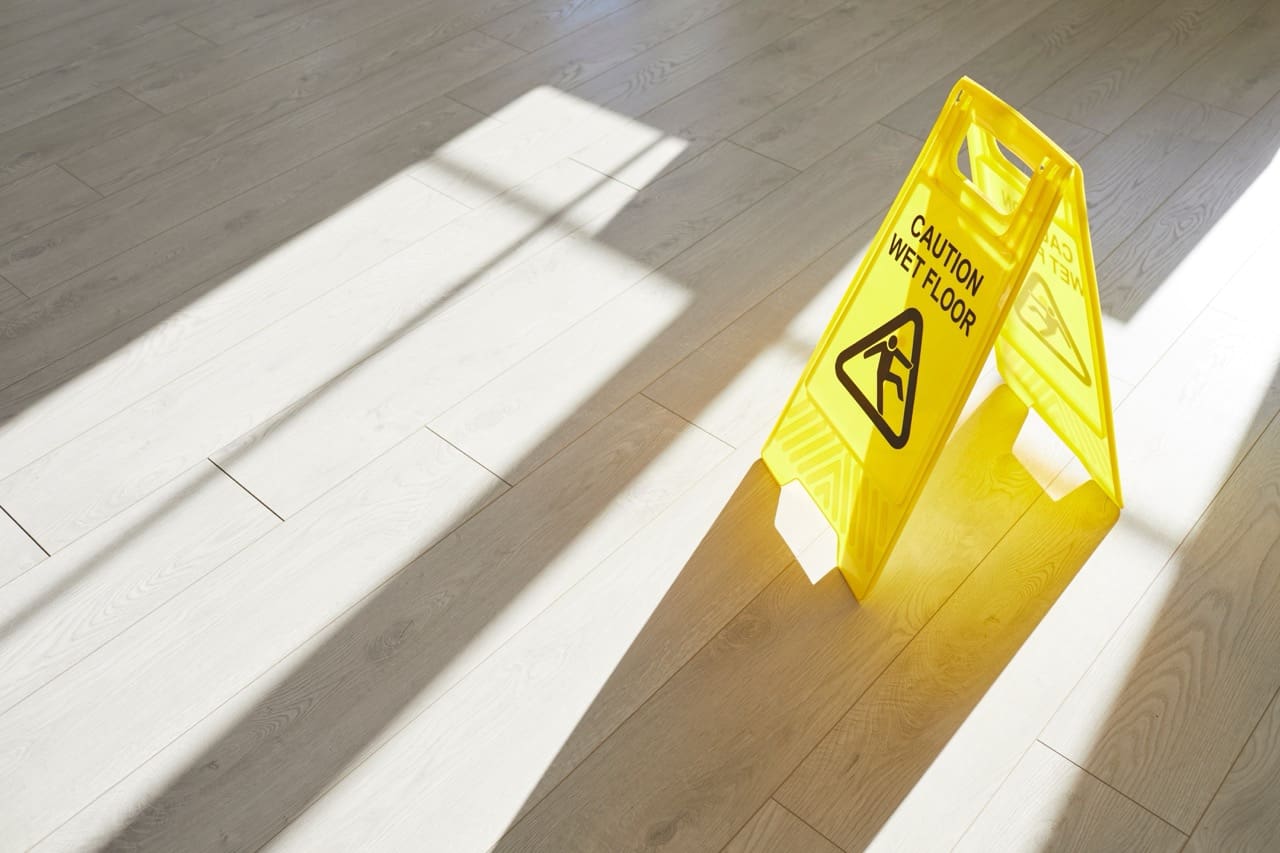 Yellow caution wet floor sign stands on the floor during maintenance, warning of slippery conditions. This safety sign helps prevent slips and fall accidents