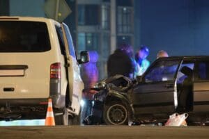 Charlotte Hit and Run Accident Lawyer - Payne Law Firm Cars crashed heavily in road accident after collision and silhouette of people on city street at night.
