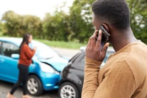 car accident between two drivers. Man on phone and women inspecting vehicle