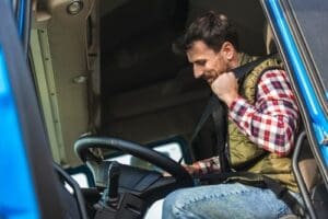Charlotte Hit and Run Accident Lawyer - Payne Law Firm Man sitting in the driver's seat of a truck, wearing a plaid shirt and vest, fastening his seatbelt inside the vehicle's cab.