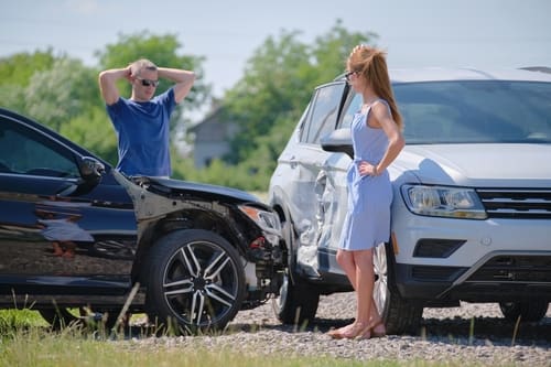 Two drivers arguing beside damaged cars after side-impact collision on roadside
