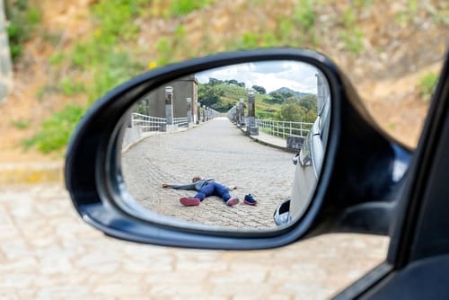 Pedestrian lying on roadway beside vehicle after traffic collision