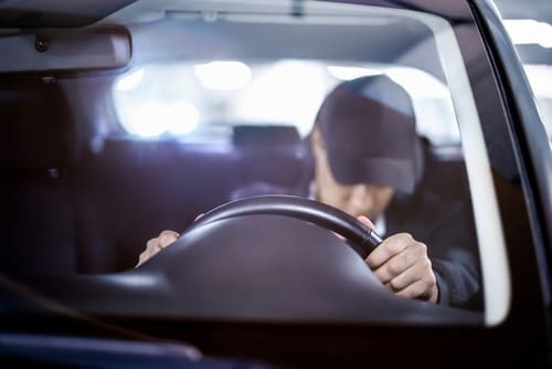 drowsy driver slumped over steering wheel inside moving vehicle