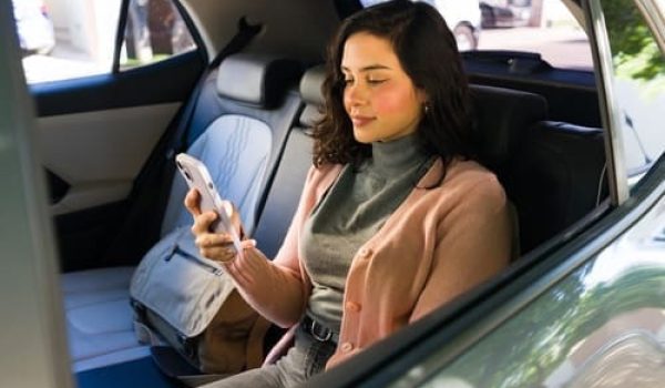 Female passenger using smartphone while seated in rideshare vehicle back seat