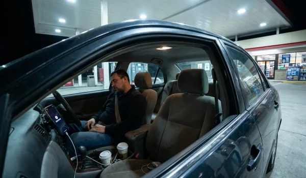 driver asleep at wheel in parked car at gas station at night