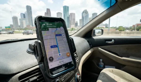 smartphone mounted on car dashboard displaying GPS navigation map app while driving