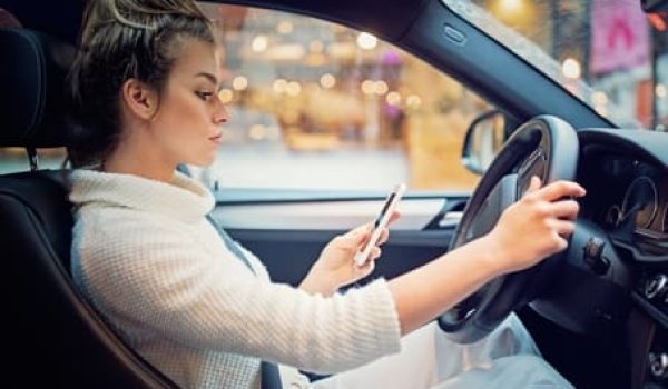 Woman texting/looking at her phone while behind the wheel